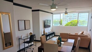 A modern living room with a dining area, a sofa, a TV, and a large window with a city view. - Cozy Elegance : Tu Rincón en San Juan (San Juan)