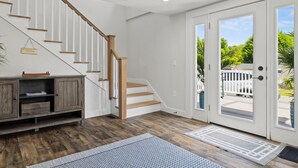 A staircase with wooden steps and a white wall, leading to a door with a view of a deck.