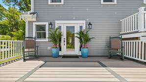 A gray house with a white door and two potted plants on the porch.