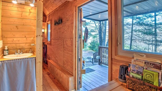 Ein Holzblock-Interieur mit Bad, einer Holzdar Terrasse und Blick auf den Wald.