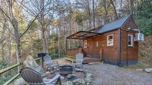 Eine Hütte mit einer Terrasse, Sitzgelegenheiten im Freien und einer Feuerstelle.