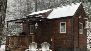 Eine rustikale Holzhütte mit einer Holzterrasse und zwei Adirondack-Stühlen.