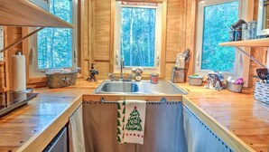 Eine gemütliche Küchenzeile in einer Holzhütte mit einem großen Fenster, einer Spüle und einem Schild mit der Aufschrift 'DREAM'.
