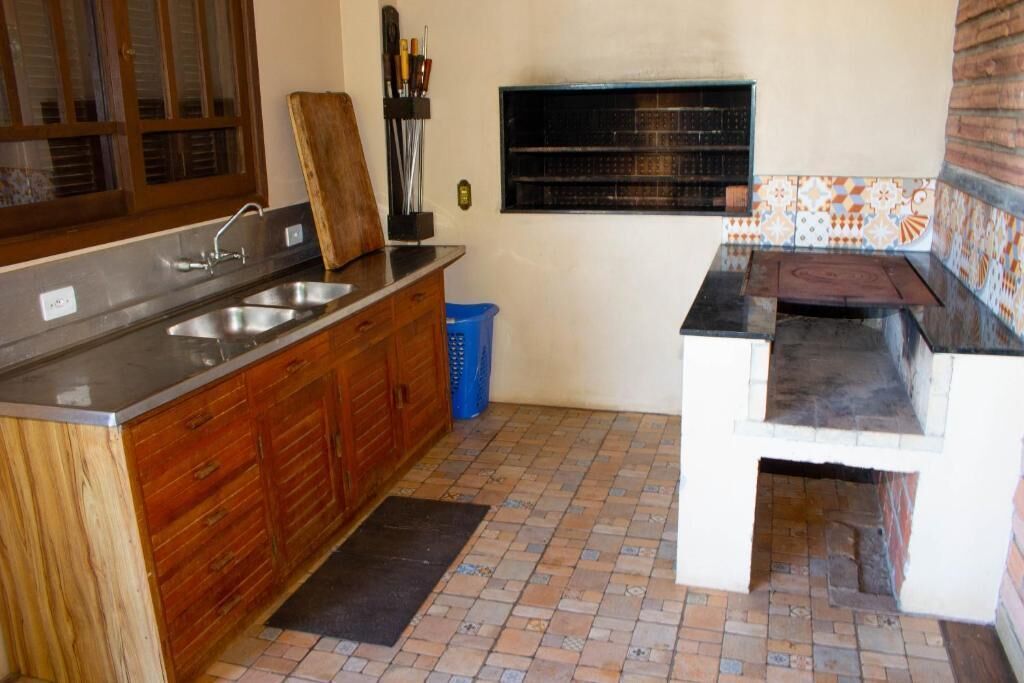 A kitchen with a wooden cabinet, a sink, a black countertop, and a tiled backsplash.