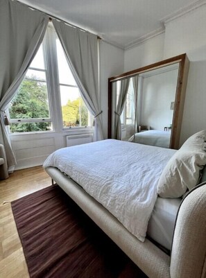 Restful retreat with a large bed and a mirror above, set against a serene backdrop.