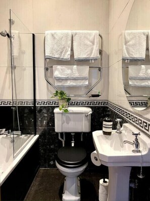 Bathroom features a glass-enclosed shower, white toilet, and sink with a silver faucet.