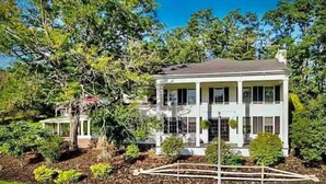 A two-story house with a symmetrical facade, large windows, and a well-maintained lawn.