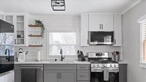 A modern kitchen with grey cabinets, a stainless steel dishwasher, a built-in oven, and a microwave. - Whole House in Bay View + Fenced-in Yard + Parking (Milwaukee)