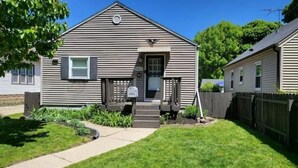 A single-story house with a front porch, a mailbox, and a small garden. - Whole House in Bay View + Fenced-in Yard + Parking (Milwaukee)