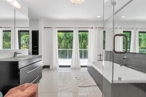 A modern bathroom with a glass shower enclosure, a large bathtub, and a vanity with a mirror. - 4BR Steps to Beach Home Private Pool, Hot Tub, BBQ (Fort Lauderdale)
