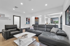 A modern living room with a sectional sofa, a glass coffee table, and a minimalist design.