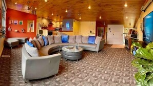A cozy living room with a curved sectional sofa, a round coffee table, and a television. - The Lookout (Galeton)