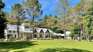 A large, white, two-story house with a spacious front lawn and multiple porches.
