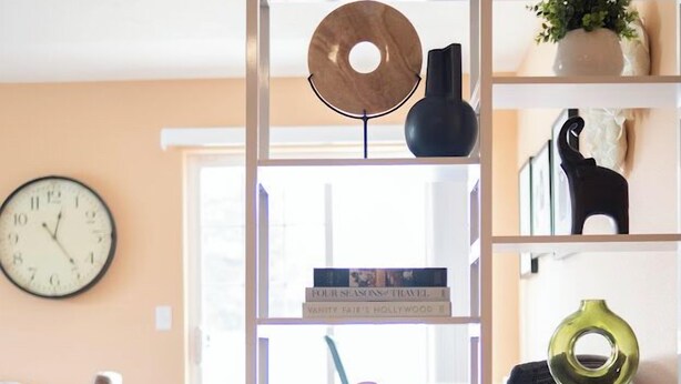 Ein Zimmer mit Bücherregal, Büchern, einer Uhr und Dekorationselementen.