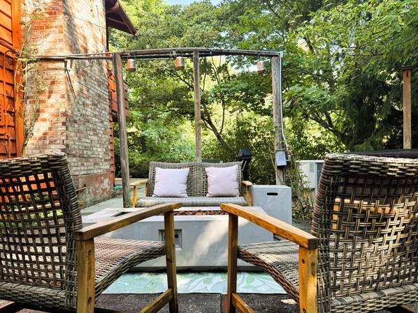An outdoor seating area with wicker furniture and a swing set.