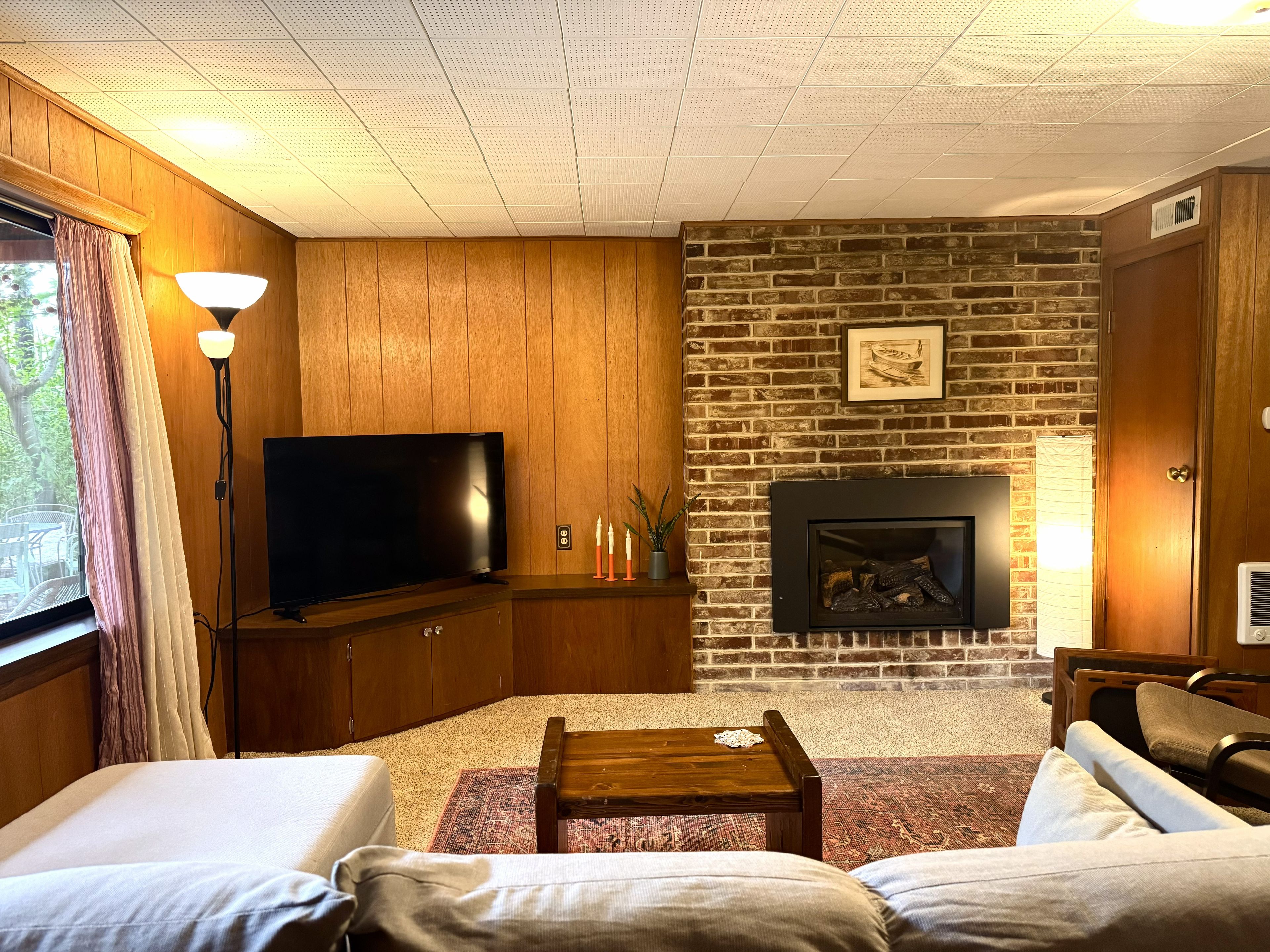 Una sala de estar con televisor, chimenea y zona de estar.