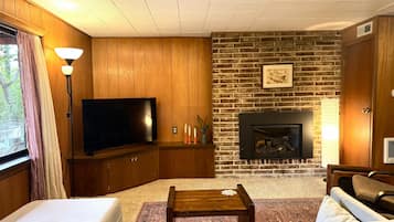 Una sala de estar con televisor, chimenea y zona de estar.