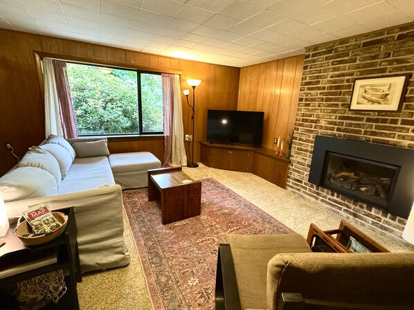 A living room with a sofa, a coffee table, a TV, and a fireplace.