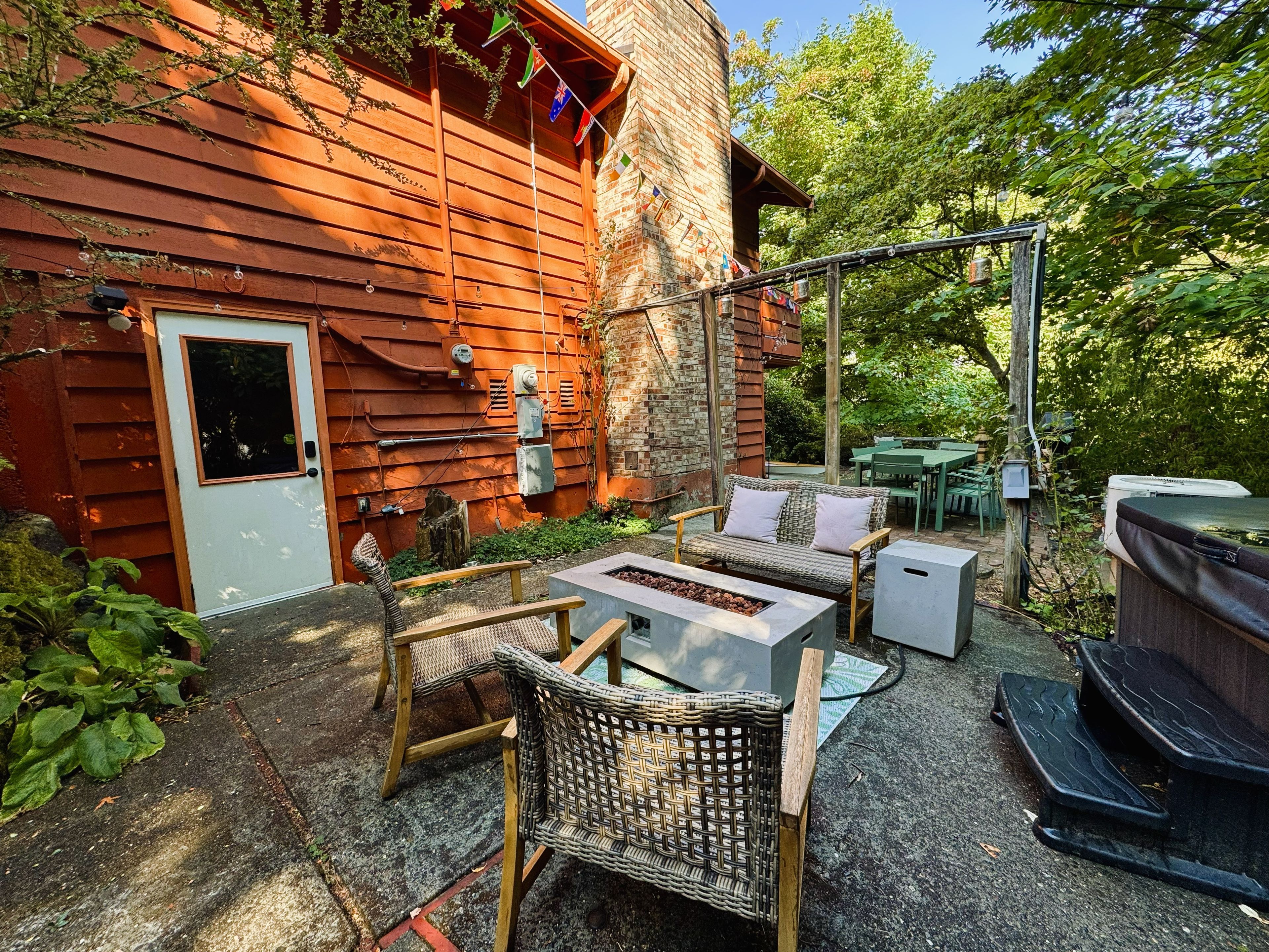 Un espace extérieur aménagé dans un style rustique, avec des meubles en osier, un foyer en béton et un barbecue.