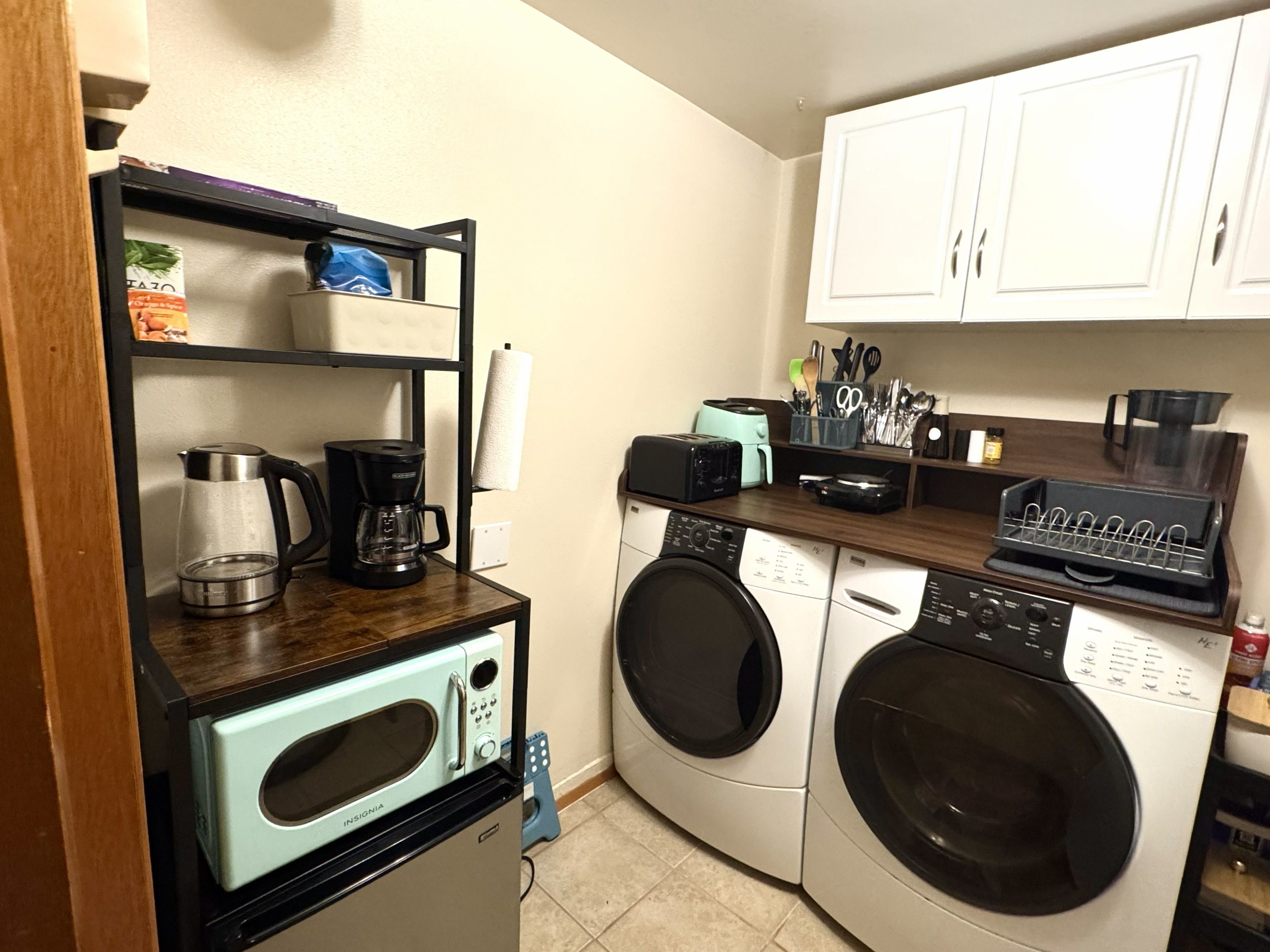 Eine kompakte Küche mit Kaffeemaschine, Toaster, Mikrowelle und Waschmaschine.