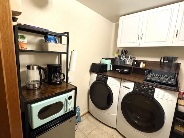Cocina compacta con cafetera, tostadora, microondas y lavadora.