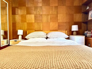 Quarto com uma cama grande, duas mesas de cabeceira, um espelho e uma mesa de apoio com abajur.