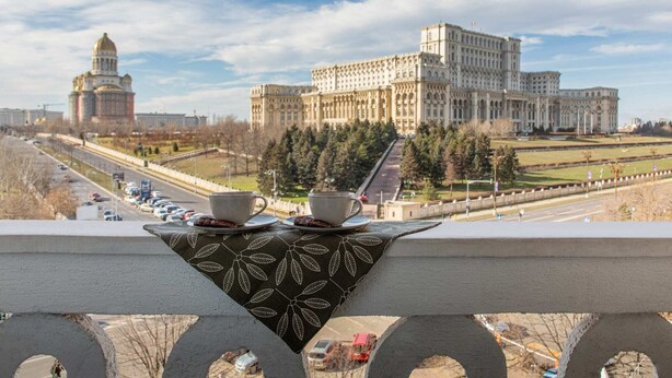 Un balcon orné d’une nappe, donnant sur un grand bâtiment doté d’un dôme et d’une structure rectangulaire.