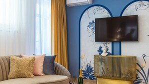 Un salon moderne avec un canapé, une table basse ronde et un téléviseur fixé au mur.