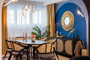 A dining area with a round table, chairs, and a decorative mirror on the wall. - Holt - Birds of Paradise (Bucharest)