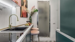 A modern kitchen with a stainless steel refrigerator, a sink with a gold faucet, and a vase with flowers on the counter. - Holt - The Great Gatsby (Bucharest)
