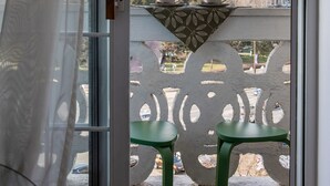 A balcony with a view of a large building, two green chairs, and a table with cups. - Holt - Bagheera and Mowgli (Bucharest)