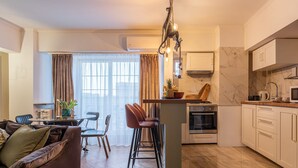 A modern kitchen with a marble backsplash, a central island with stools, and a dining area with a sofa and chairs. - Holt - Bagheera and Mowgli (Bucharest)