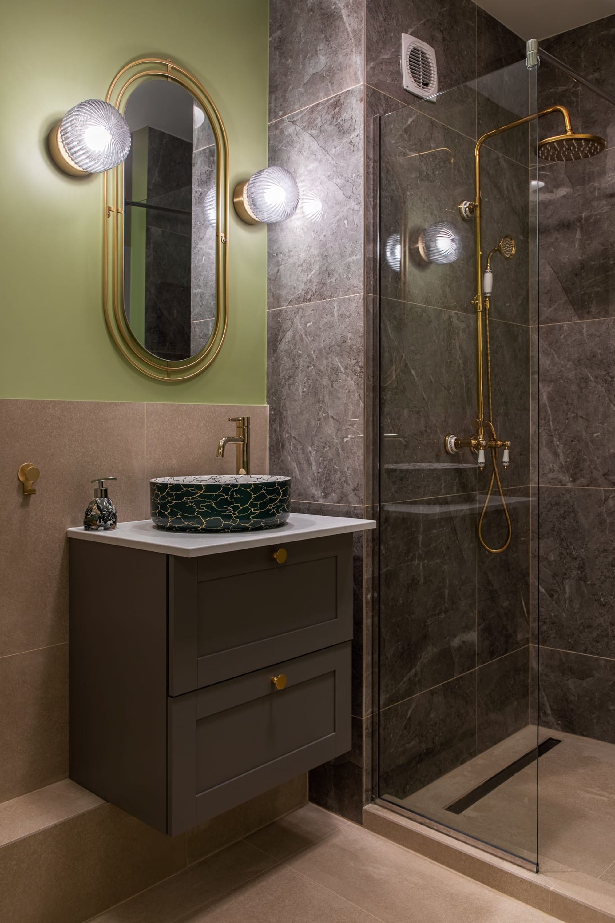 Un bany modern amb un mirall rodó, un lavabo amb taulell de marbre i una zona de dutxa amb envàs de vidre.