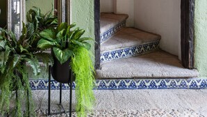 Una habitación con pared verde, un espejo, una escalera y una planta en maceta.