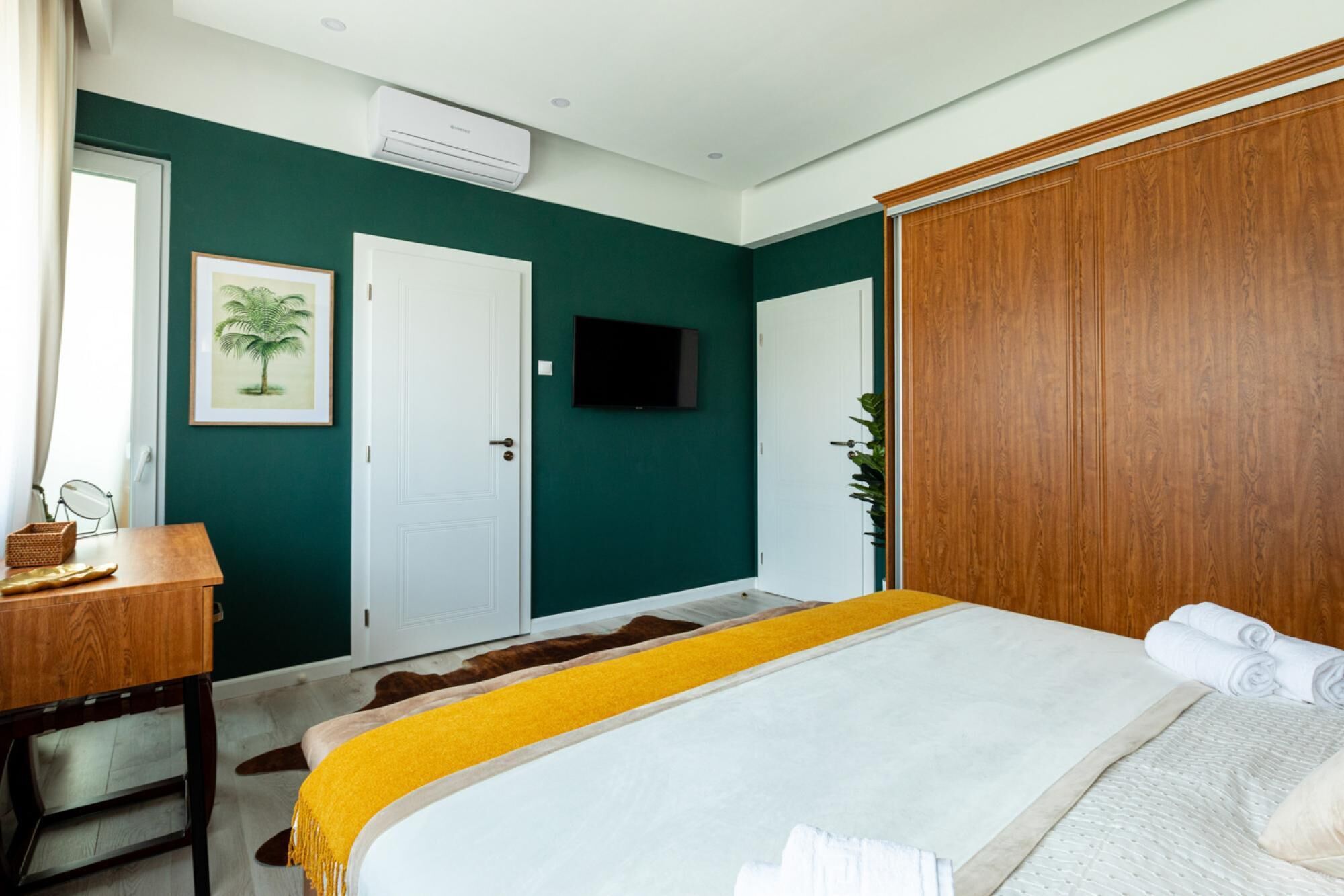 A bedroom with a bed, a desk, a television, and a wardrobe.