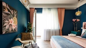 Quarto com uma cama, uma cadeira, uma planta e um quadro na parede.