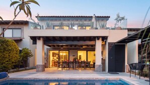 Uma casa moderna com piscina, pátio e área de jantar coberta ao ar livre.