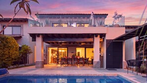 Uma casa moderna com piscina, varanda e área de jantar coberta ao ar livre.