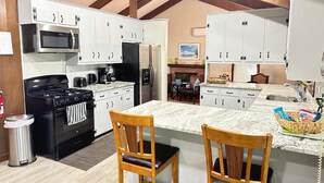 A kitchen with white cabinets, a black stove, a microwave, and a granite countertop.