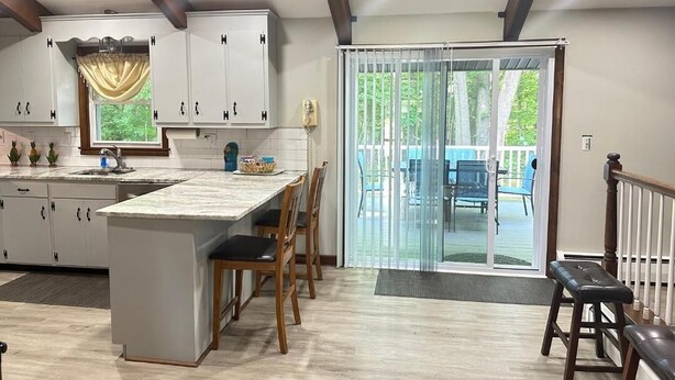 A kitchen with a central island, wooden chairs, a dining table, and a sliding glass door leading to an outdoor area.