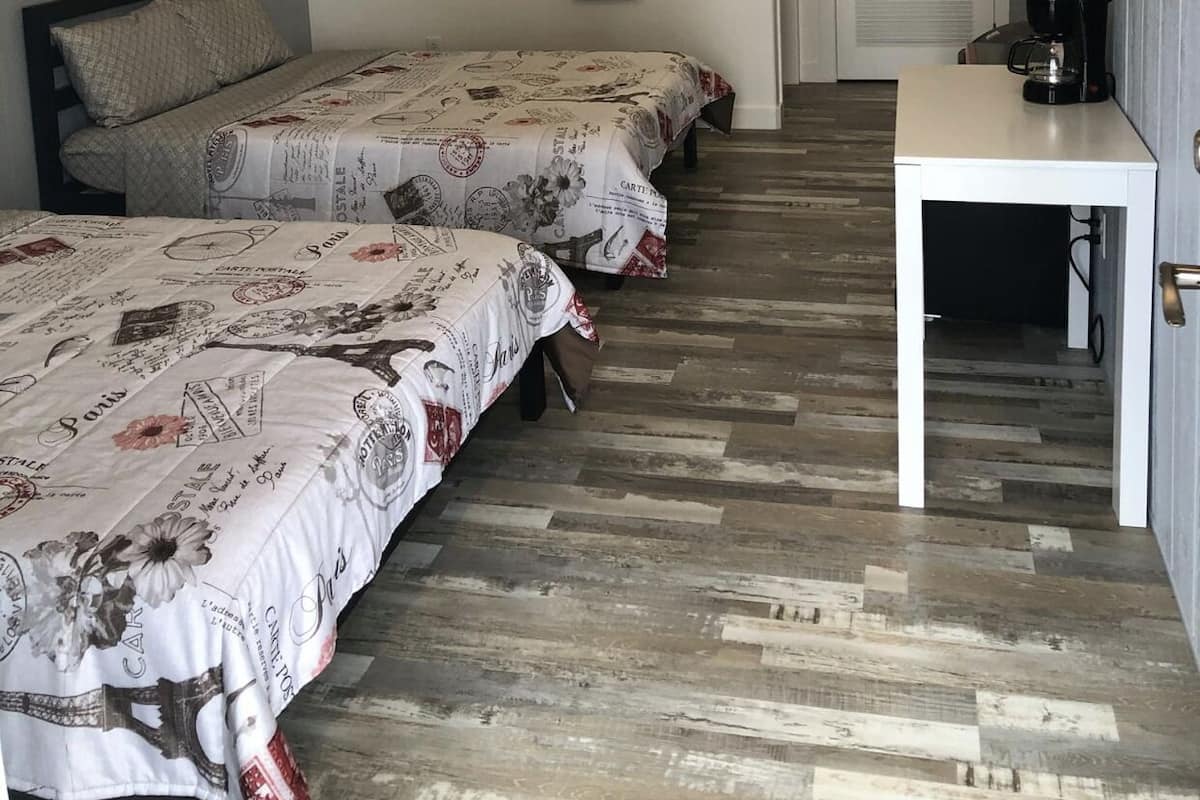 Une chambre d’hôtel avec deux lits, une petite table, une machine à café et un purificateur d’air fixé au mur.