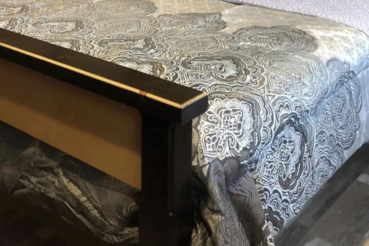 Une chambre à coucher avec une couvre-lit à motifs, une tête de lit en bois et un panneau décoratif mural.