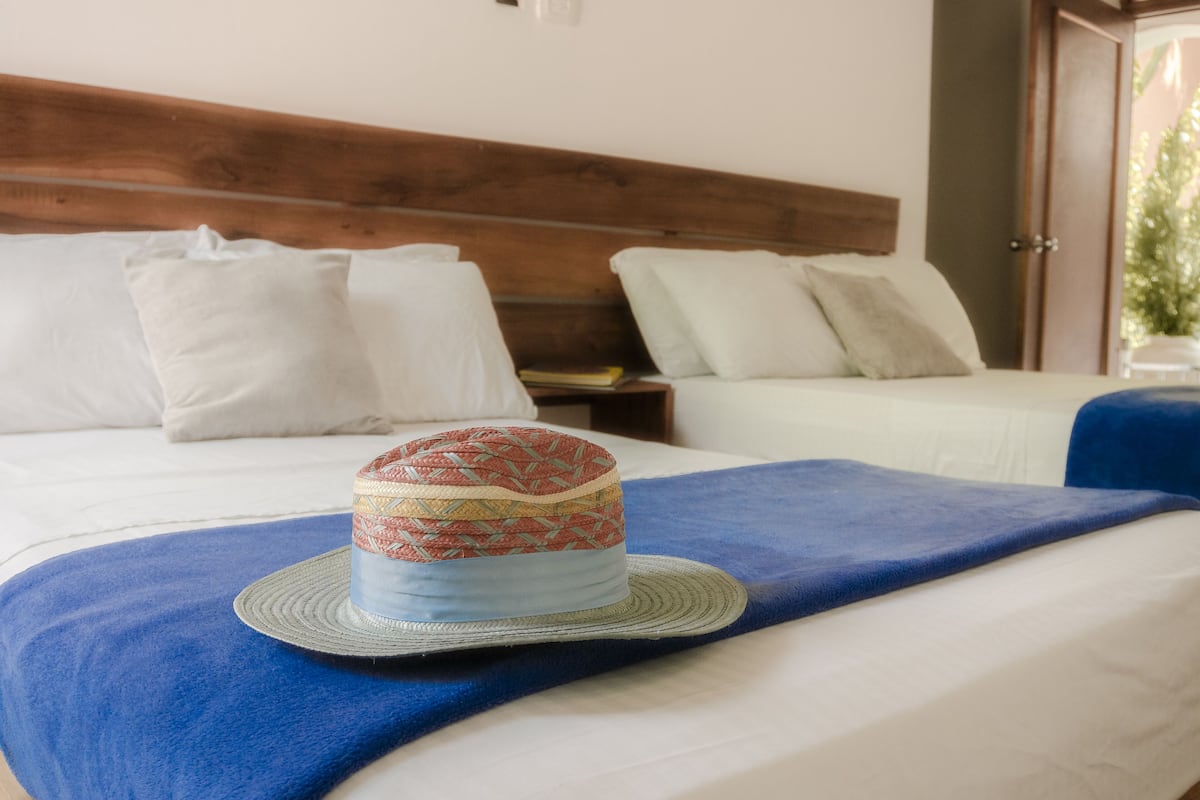 Hotellihuone, jossa on kaksi sänkyä, puinen pääty ja sininen koristepeto.