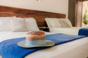 Ein Hotelzimmer mit zwei Betten, einem Holzkopfteil und einer blauen Decke.