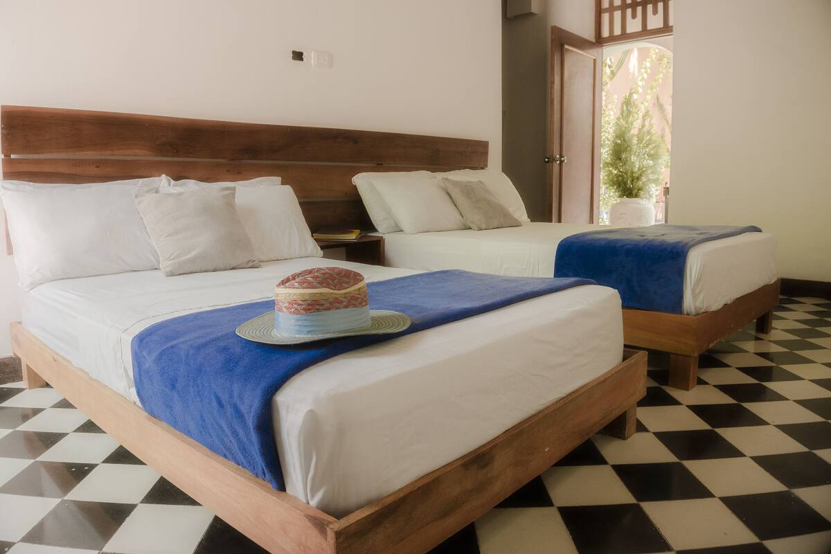 A room with two wooden beds, white bedding, and a checkered floor.