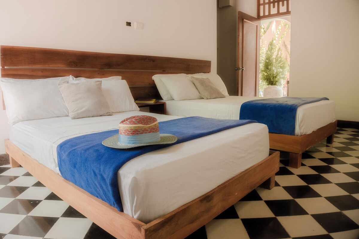 A room with two wooden beds, white bedding, and a checkered floor.
