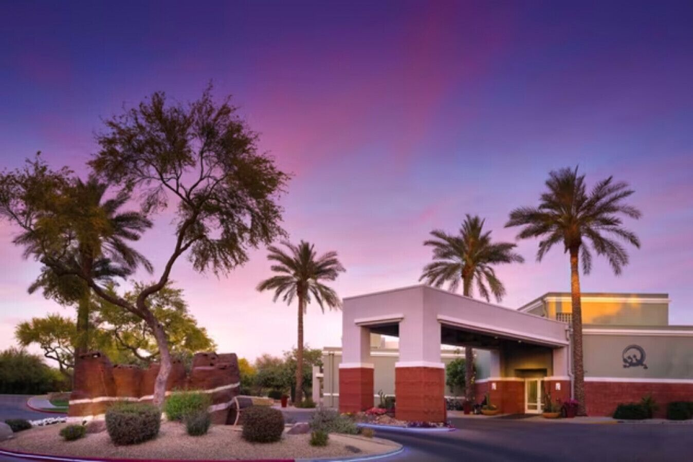 A hotel with a modern architectural style, featuring a flat roof and a mix of brick and white exterior walls.
