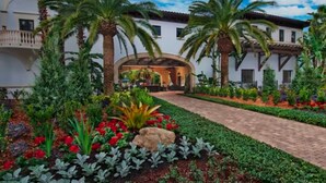 Un hotel con un patio central, palmeras y una variedad de flores coloridas.