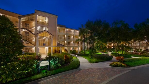 A multi-story hotel with a central atrium, outdoor landscaping, and a paved driveway.