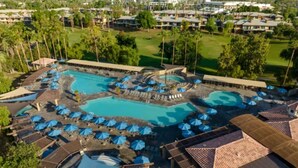 Ein Resort mit mehreren Swimmingpools, Sonnenschirmen und Liegebereichen.